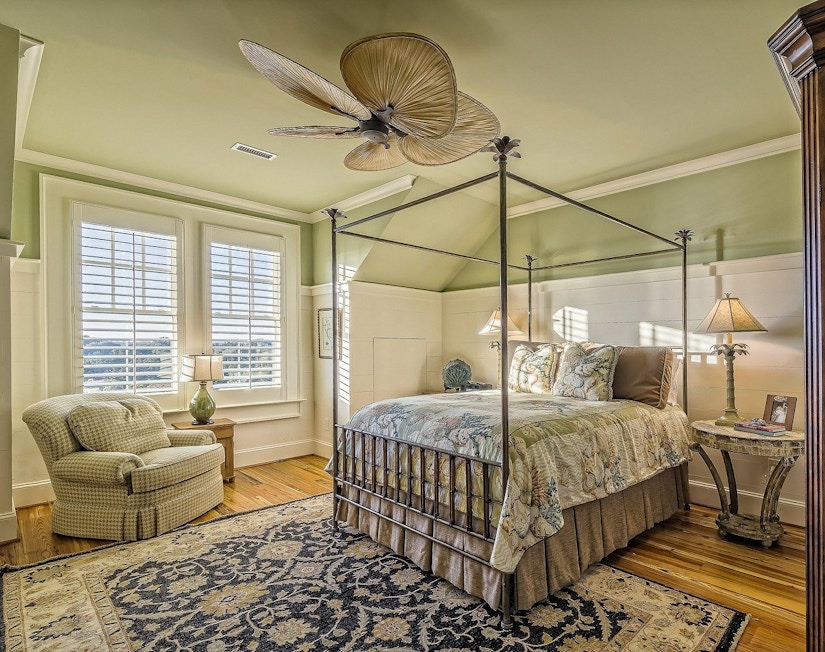Helles Schlafzimmer mit Teppich, blassgrüner Decke, Deckenventilator und Boxspringbett