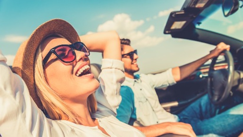 Ein Pärchen sitzt im offenen Cabrio und lacht