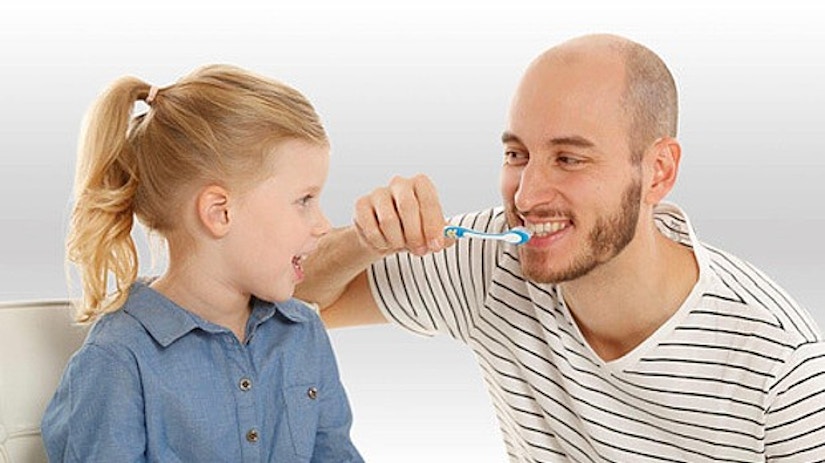 Ein Vater zeigt seiner Tochter, wie man Zähne putzt.