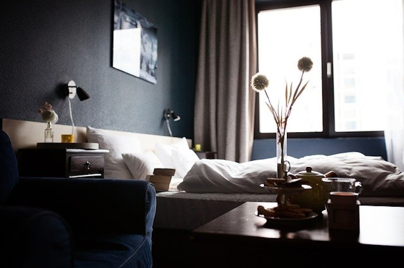 Hotelzimmer- Bett, Sessel, Tisch mit Blumen