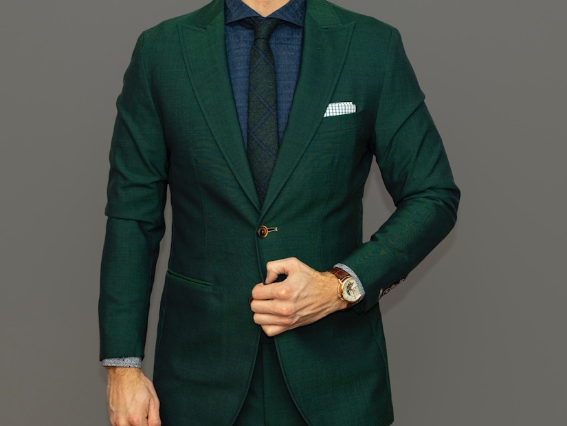 Mann in grünem Anzug mit dunkelblauem Hemd und schwarzer Krawatte