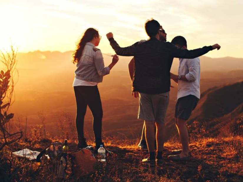 Freunde tanzen auf dem Hügel beim Sonnenuntergang