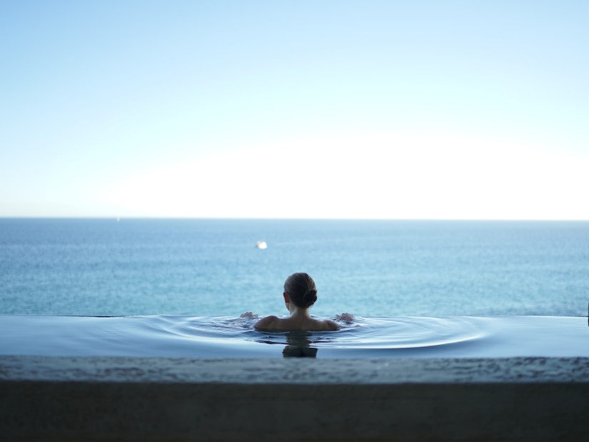 Frau im Pool mit Blick auf das Meer
