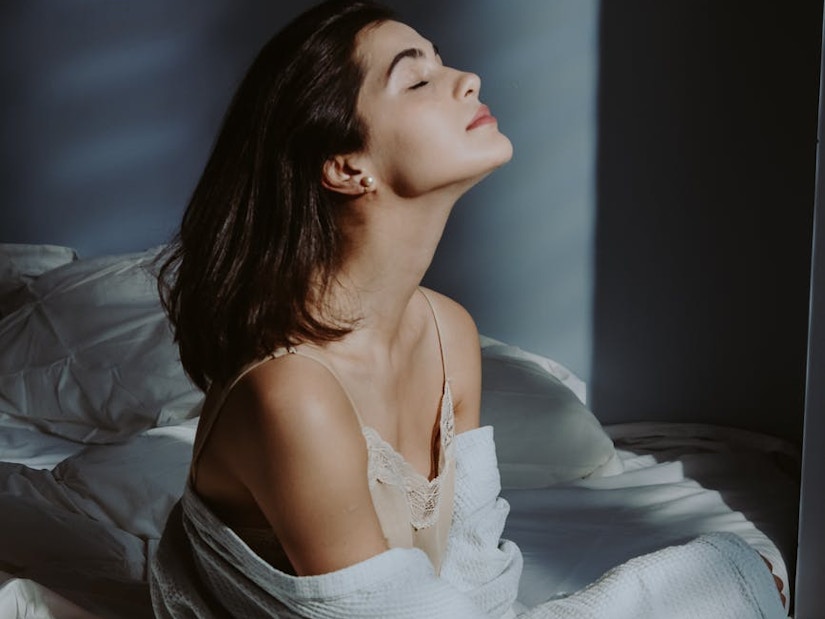 Eine Frau im Nachthemd sitzt auf dem Bett