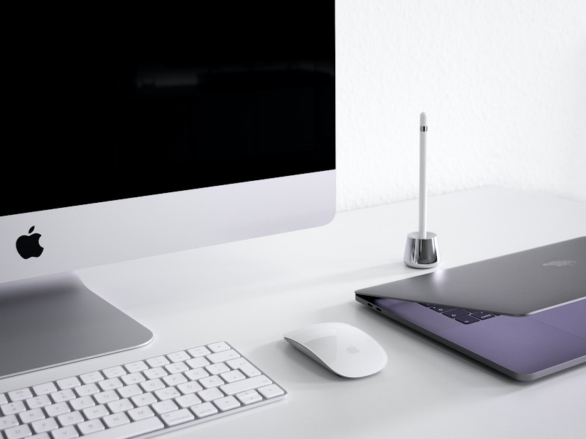 Auf dem Tisch liegen iMac mit der Maus und Tastatur und ein Macbook 