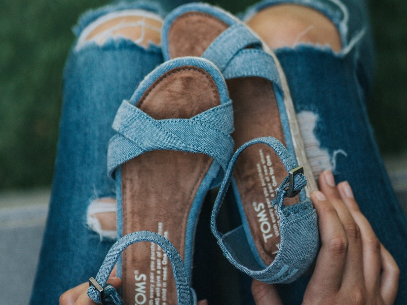 Eine Frau hält ein Paar blaue Sandalen 
