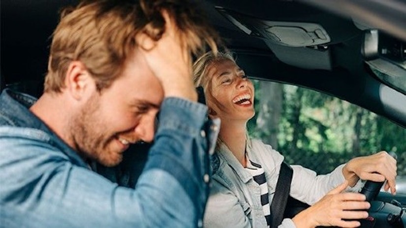 Ein Pärchen sitzt im Auto und lacht.