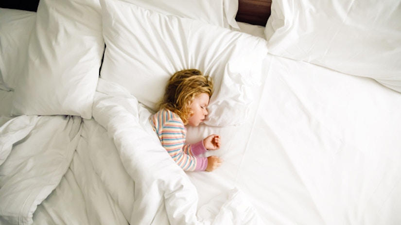 Ein Mädchen schläft in einem Hotelbett.