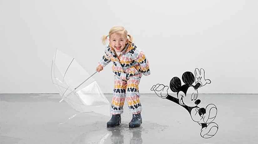 Ein Mädchen mit Regenschirm und Regenkleidung und Mickey Mouse.