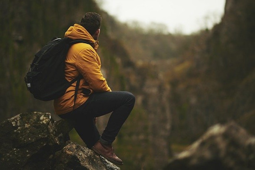 Wanderer mit gelber Jacke und Rucksack in den Bergen