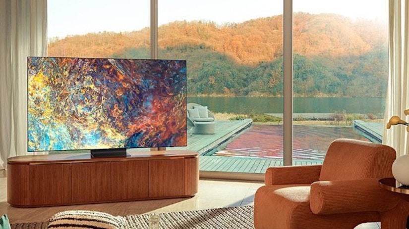 Ein Wohnzimmer mit Fernseher und Sessel mit Blick auf Wasser. 