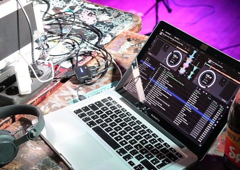 Laptop mit laufender DJ-Software und Audio-Zubehör