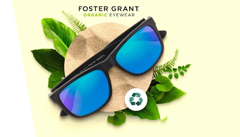 Reflexierende Sonnenbrille mit Umwelt-Logo auf grünen Blättern.