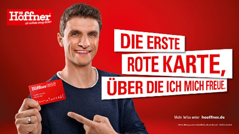 Thomas Müller hält die rote Höffner Kundenkarte in der Hand und freut sich
