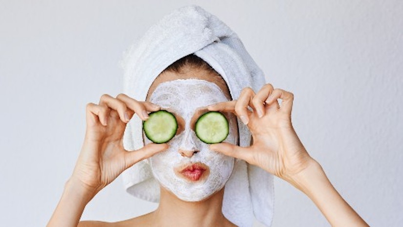 Eine Frau mit Gesichtsmaske und Gurken auf den Augen