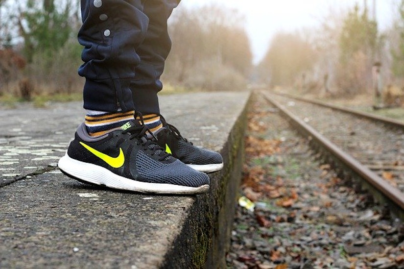 Nahaufnahme auf Nike Sneaker an herbstlicher Bahnstrecke