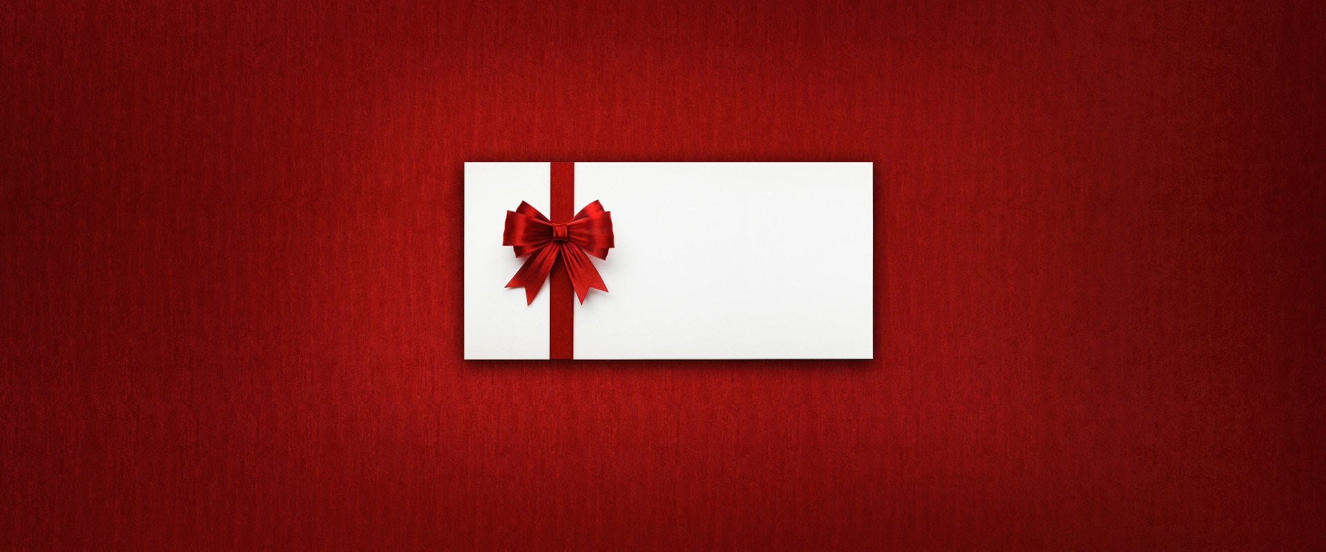Ein Geschenkgutschein mit Schleife auf rotem Hintergrund.