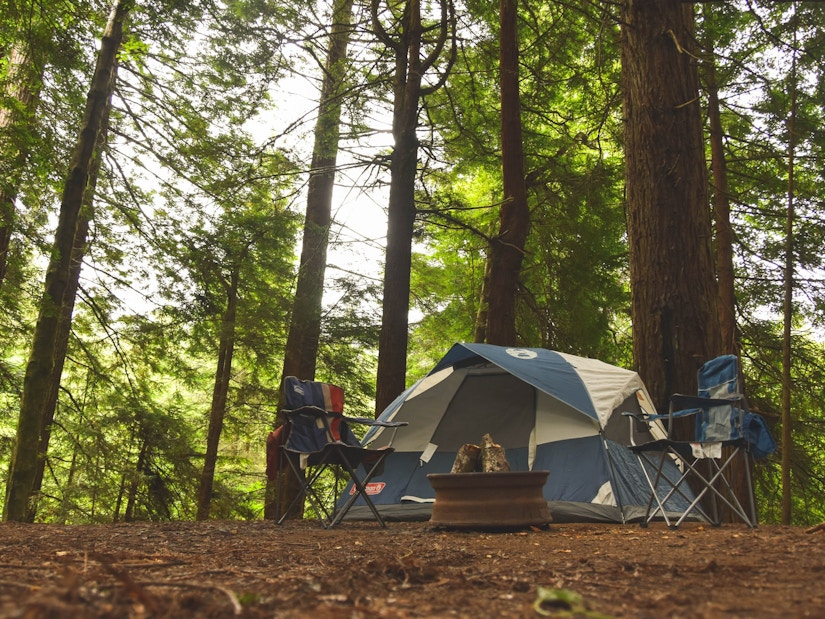 Campingzelt und zwei Campingstühle im Wald