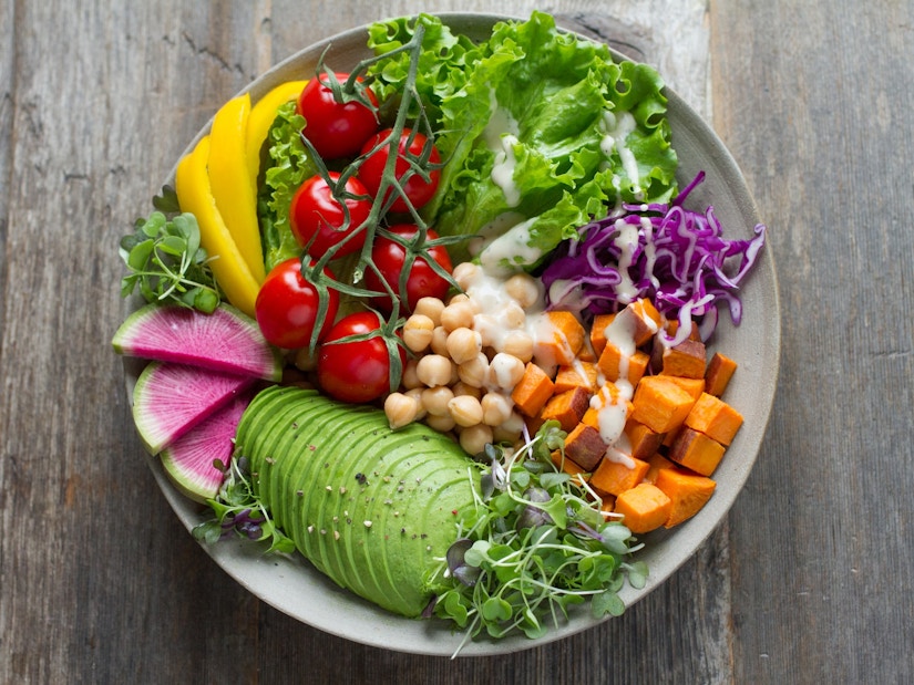 Teller mit Blattsalat, Avocado, Paprika und weiteren veganen Lebensmitteln